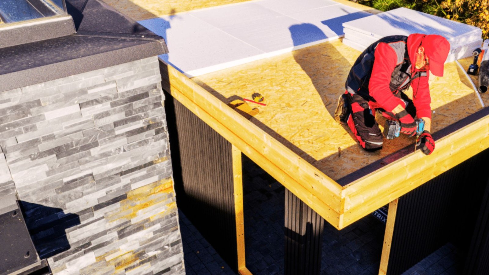 Plywood decking being installed over a flat roof frame.