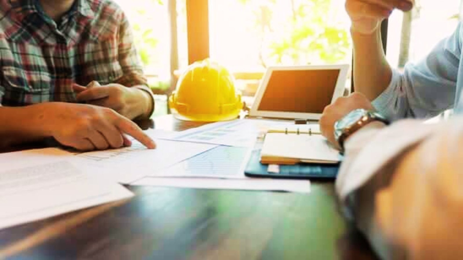 Owner, architect, and contractor reviewing project schedules, budgets, and construction updates during an OAC meeting.