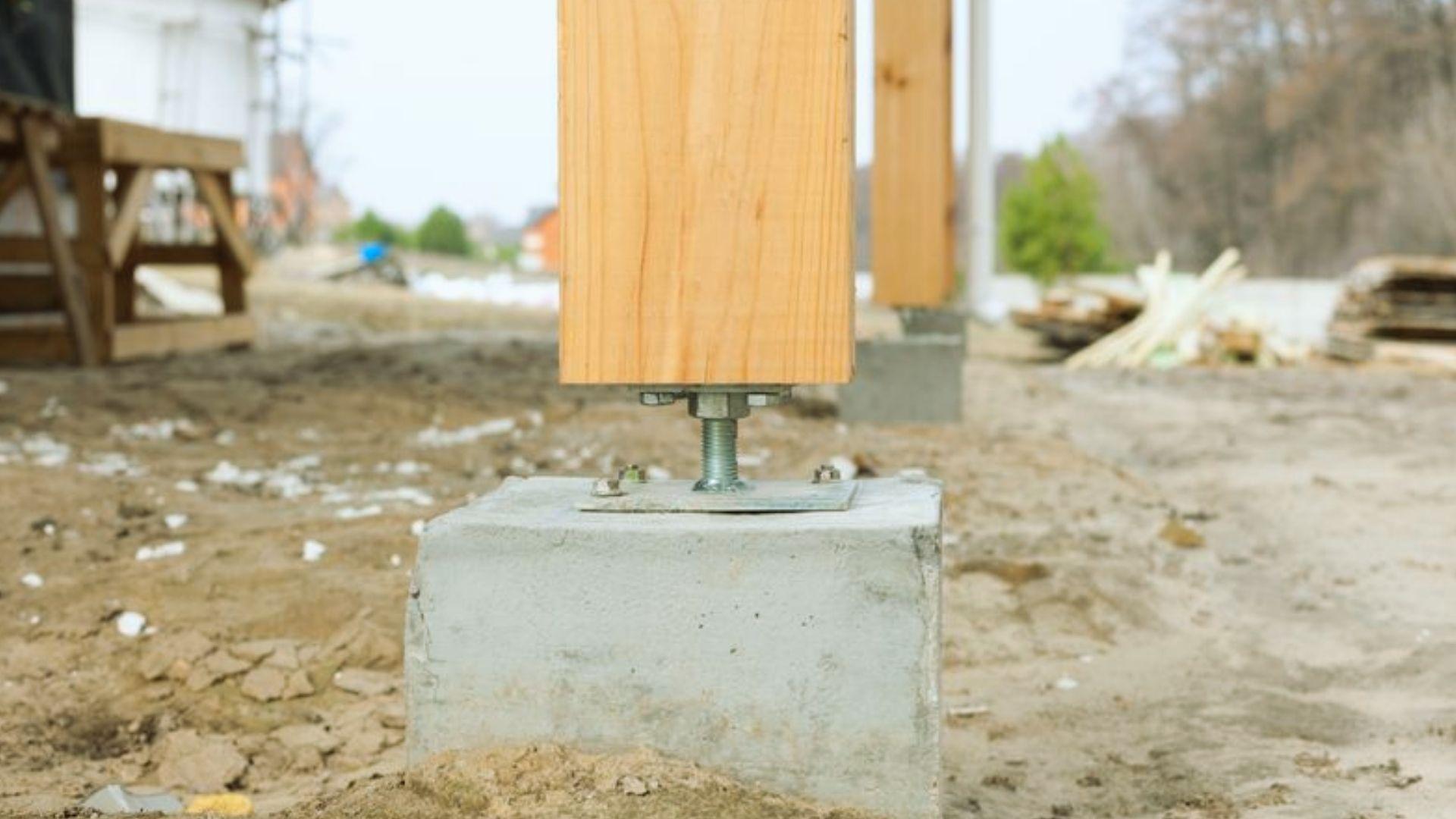 Wooden post on concrete pier foundation with adjustable steel anchor bolt at construction site