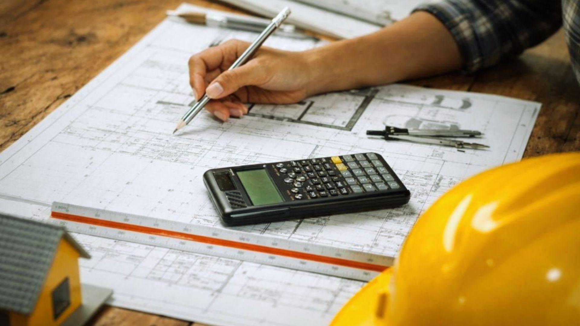 Architect drawing house blueprint with calculator hard hat and model home