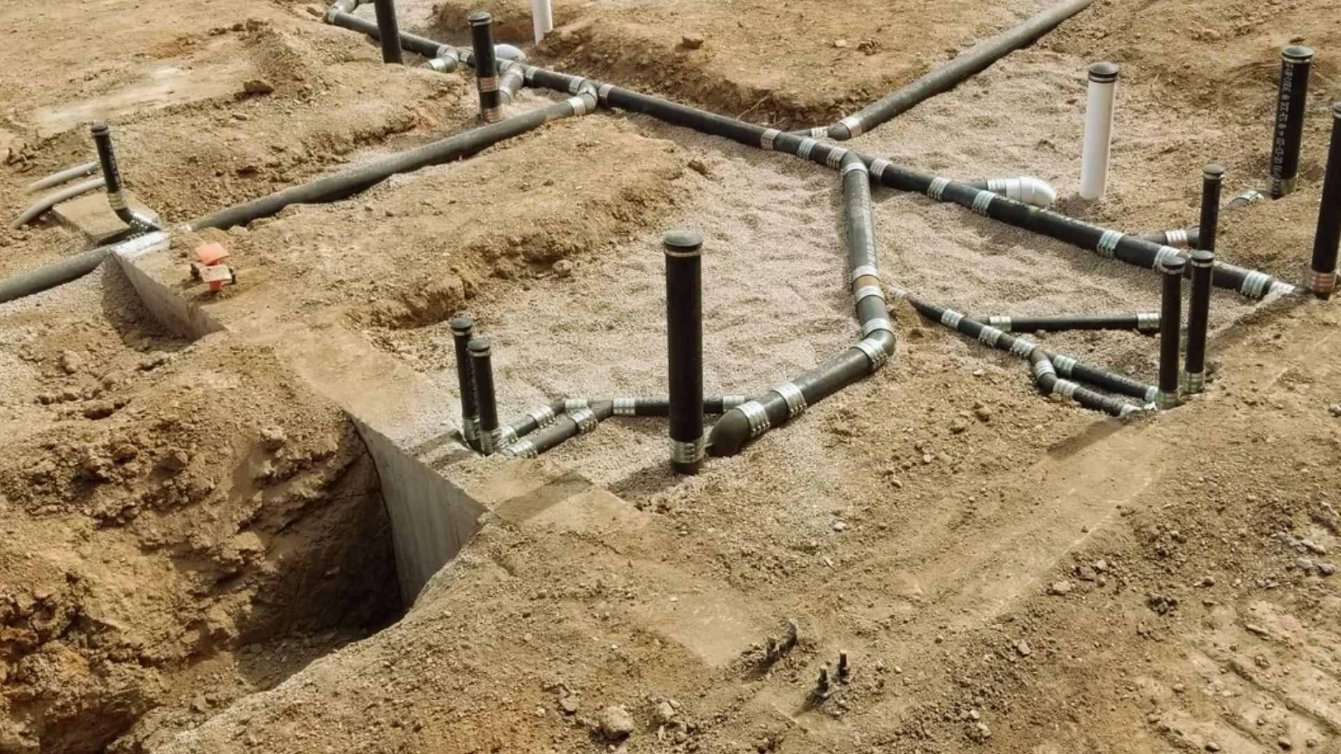 Underground plumbing pipes installation at residential foundation construction site with dirt trenches