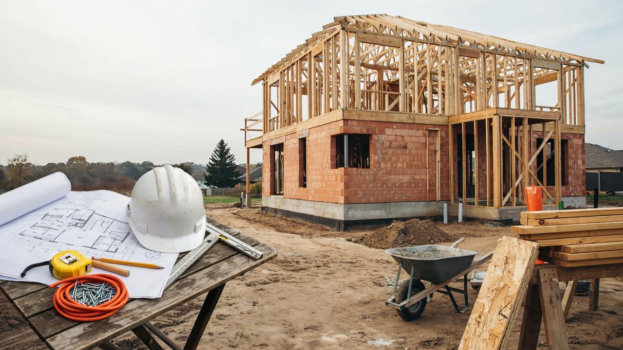 Home construction site with building plans and tools representing the process of hiring a home builder.
