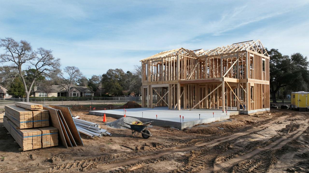 New home construction site showing foundation and early framing stages of a house.