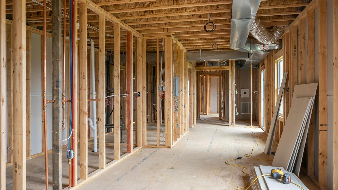 Partially finished home interior with plumbing, electrical wiring, HVAC ducts, and interior construction work.