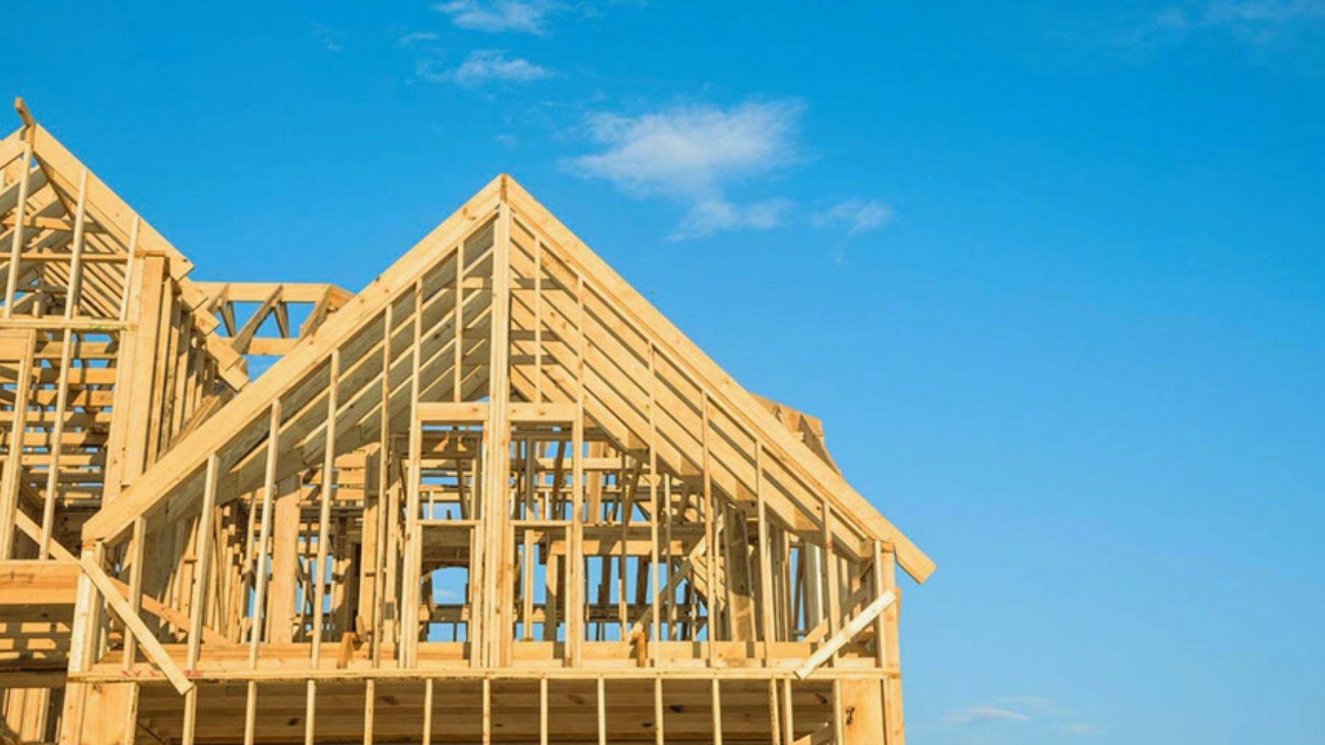 New house wood framing construction with gable roof trusses under bright blue sky