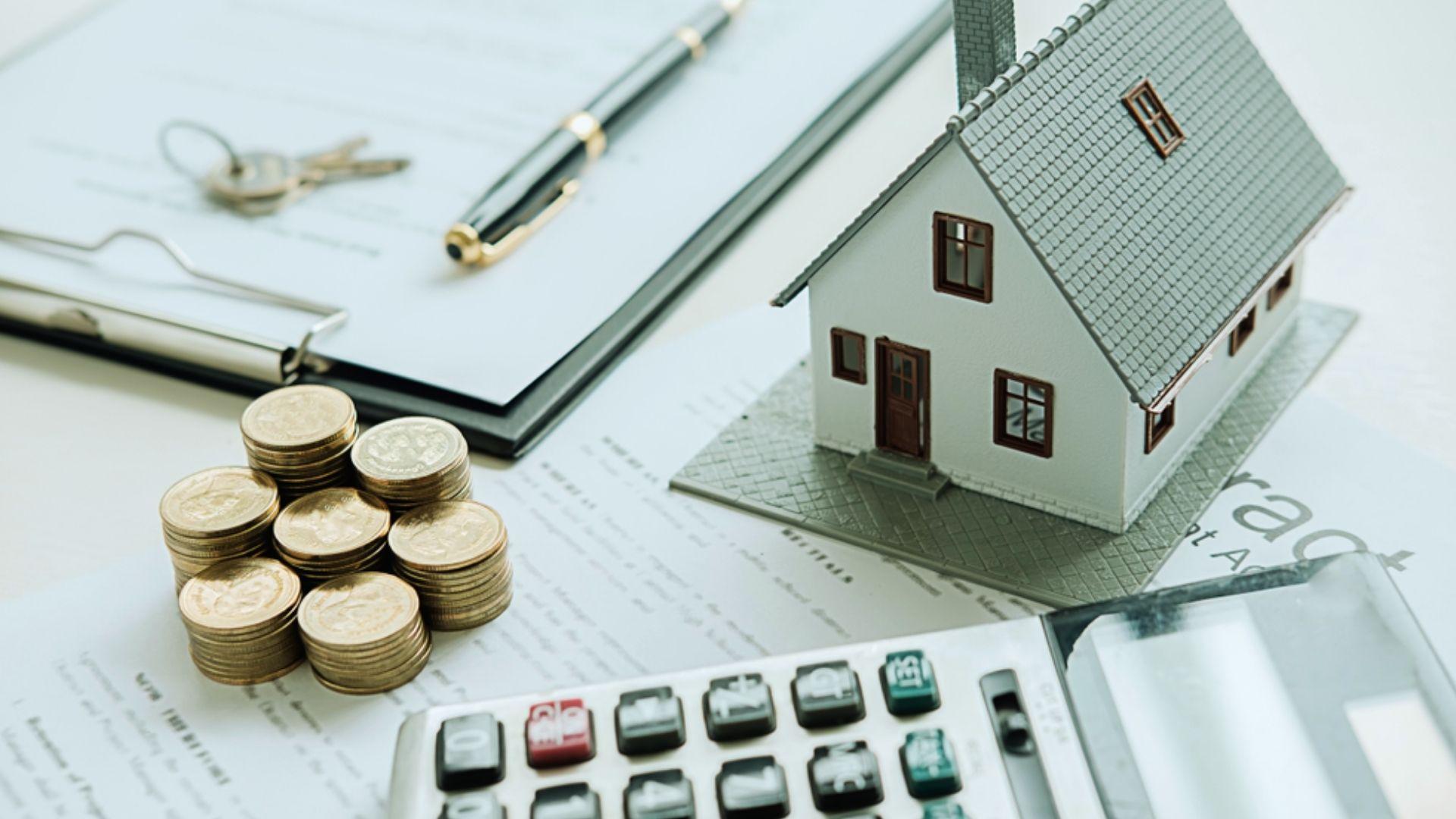Miniature house model with stacked coins calculator and contract for home purchase budgeting
