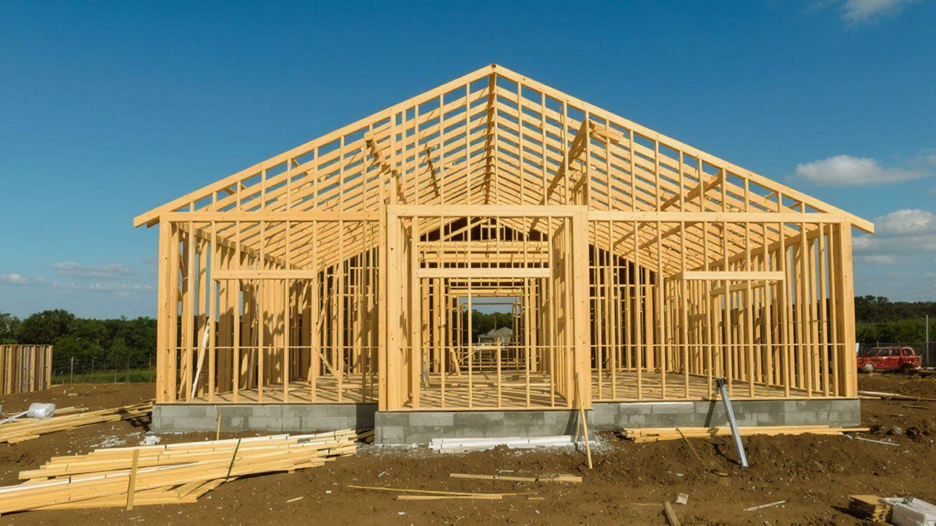 Wooden house frame construction with gable roof trusses on concrete block foundation at building site