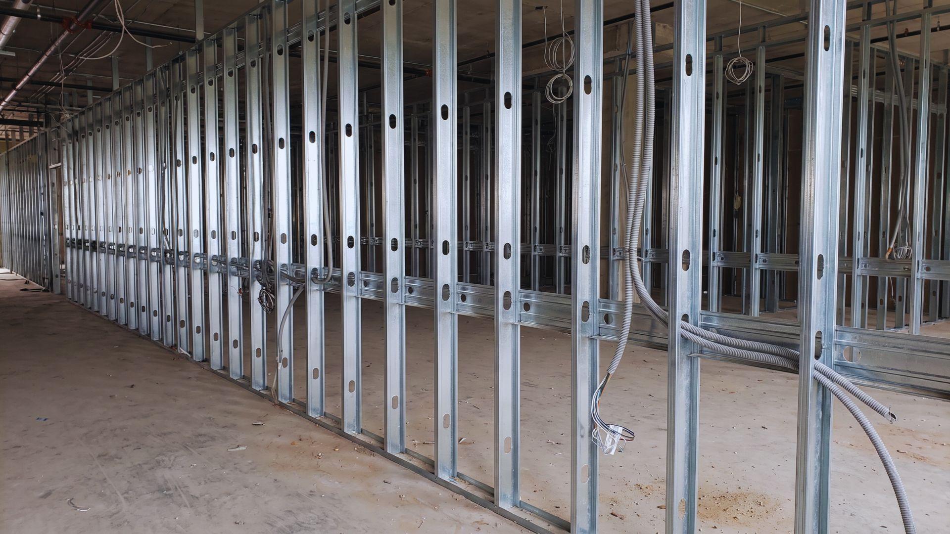 Galvanized steel studs with punched openings for electrical conduit in an unfinished commercial office.