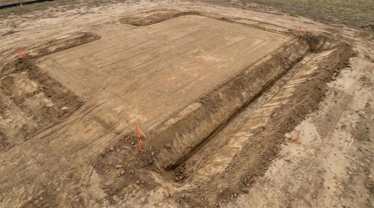 Graded construction site with compacted ground and clear drainage path.