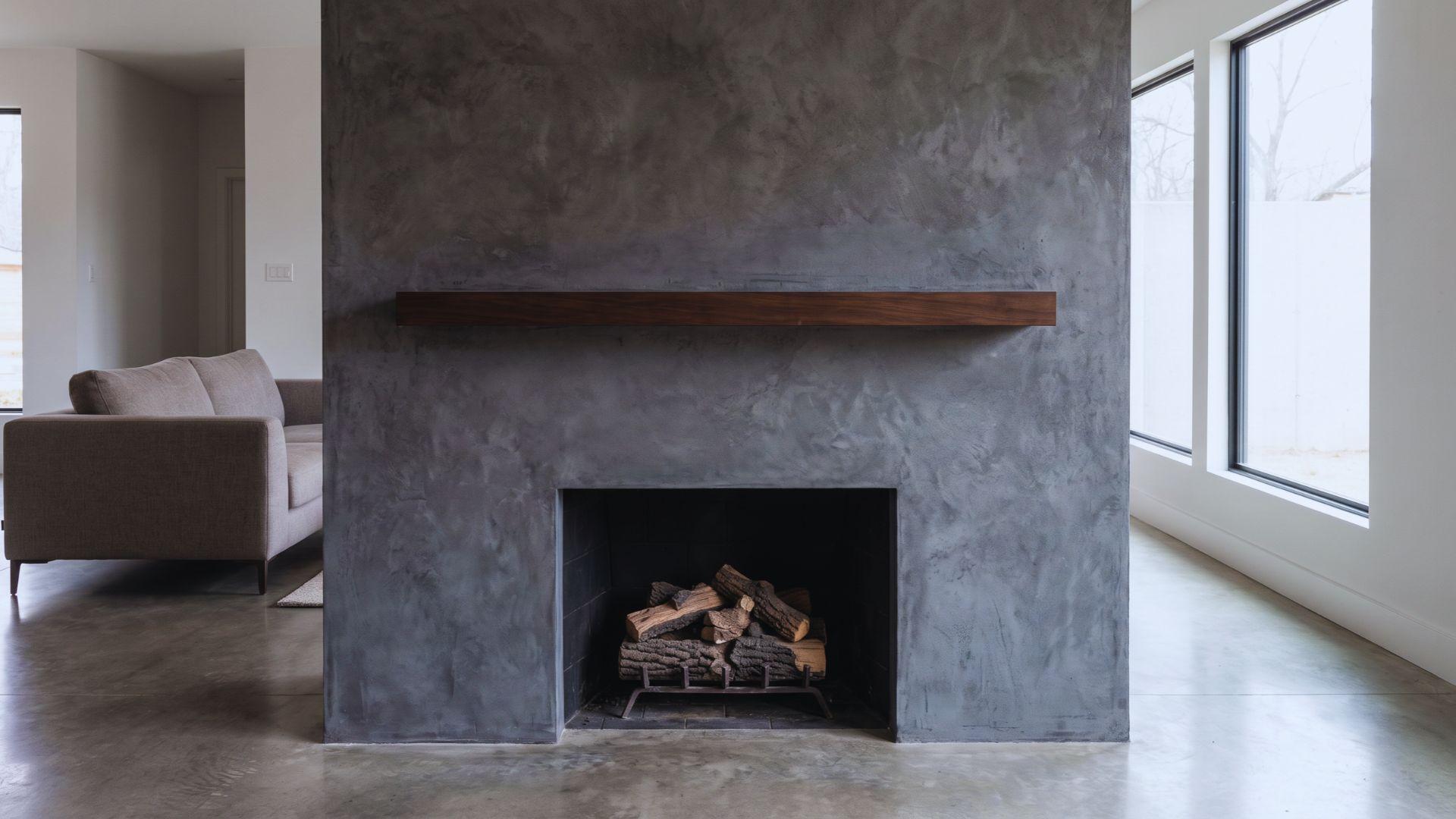Dark grey coarse Marmorino plaster fireplace surround with a low-gloss concrete-like texture.