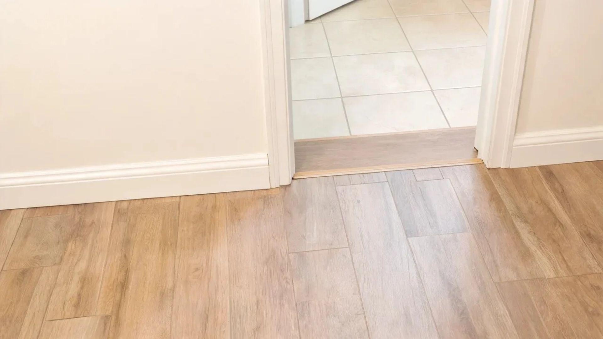 Vinyl plank flooring with baseboard trim and a transition strip at a doorway.File name: vinyl-flooring-trim-transitions