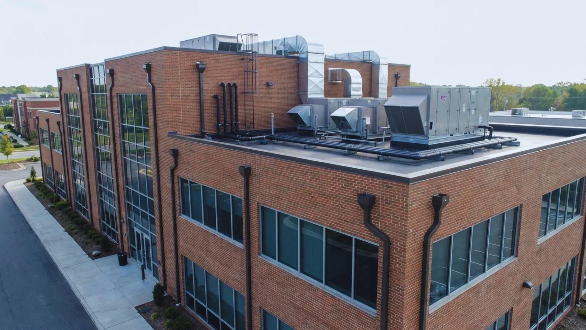 Commercial office building with rooftop HVAC equipment and exterior drainage systems.File name: commercial-building-maintenance
