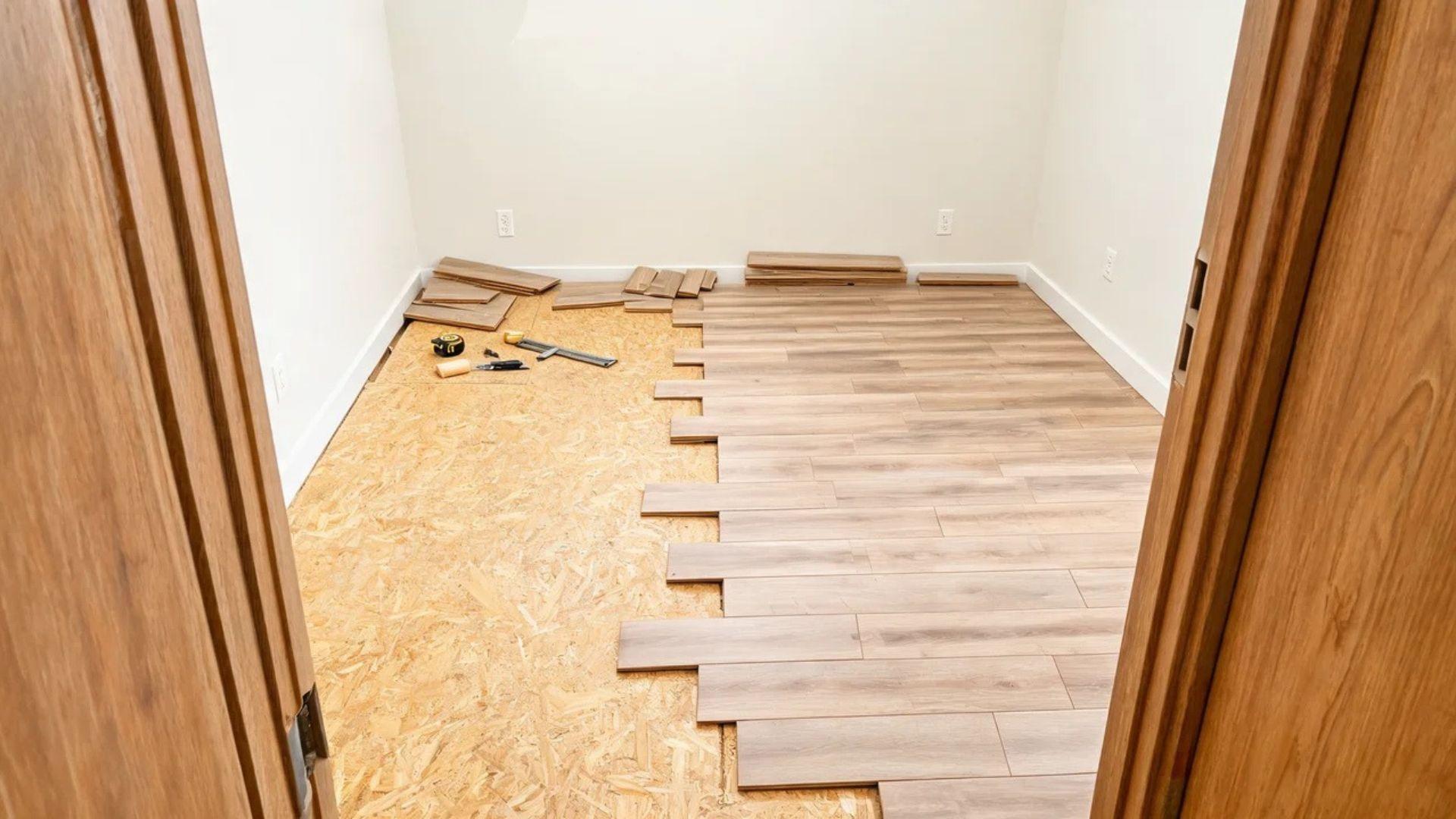 Vinyl plank flooring partially installed in a rectangular room with tools and cut planks nearby.File name: vinyl-flooring-installation-labor