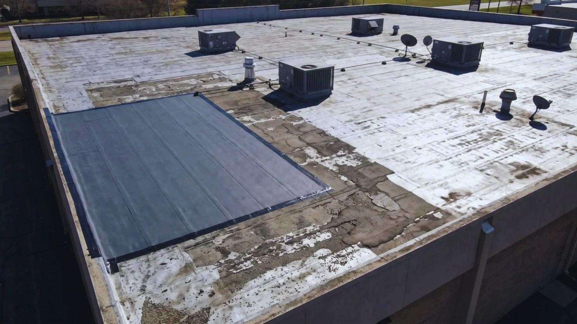 Commercial flat roof with a localized membrane repair area and worn roofing sections.File name: commercial-roof-repair-replacement