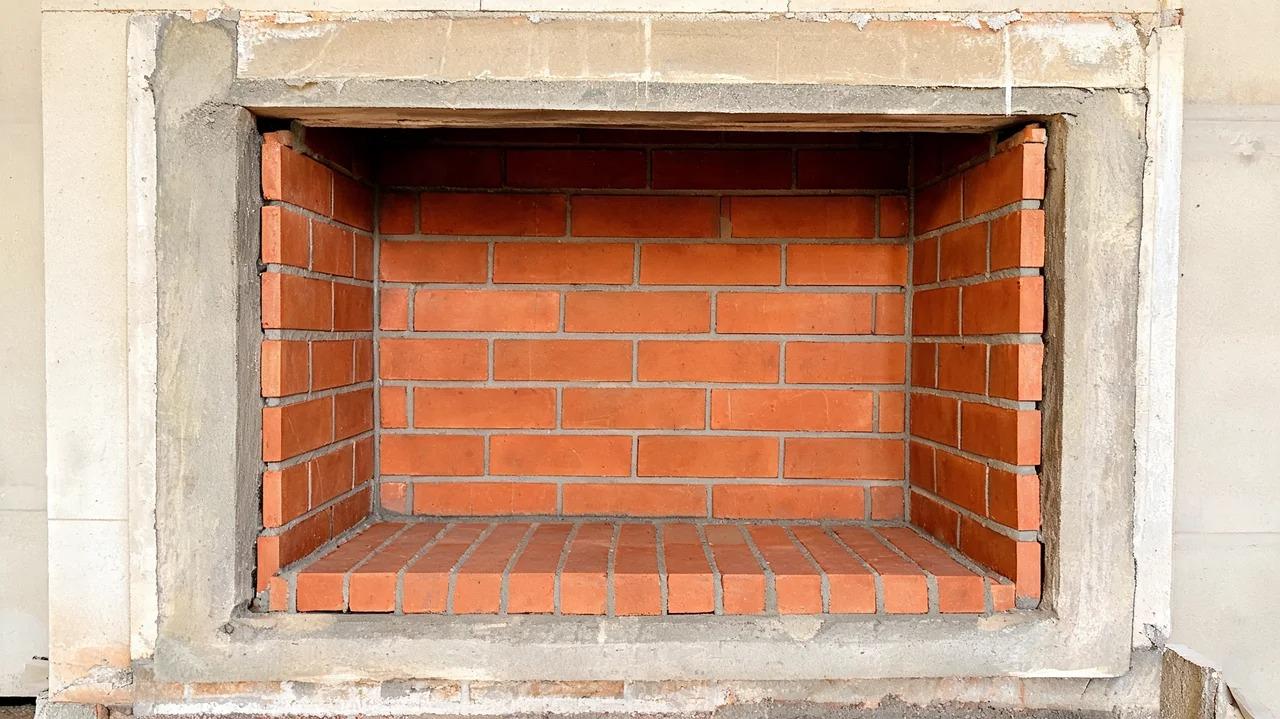 Firebrick firebox inside an indoor masonry fireplace with thin refractory mortar joints.