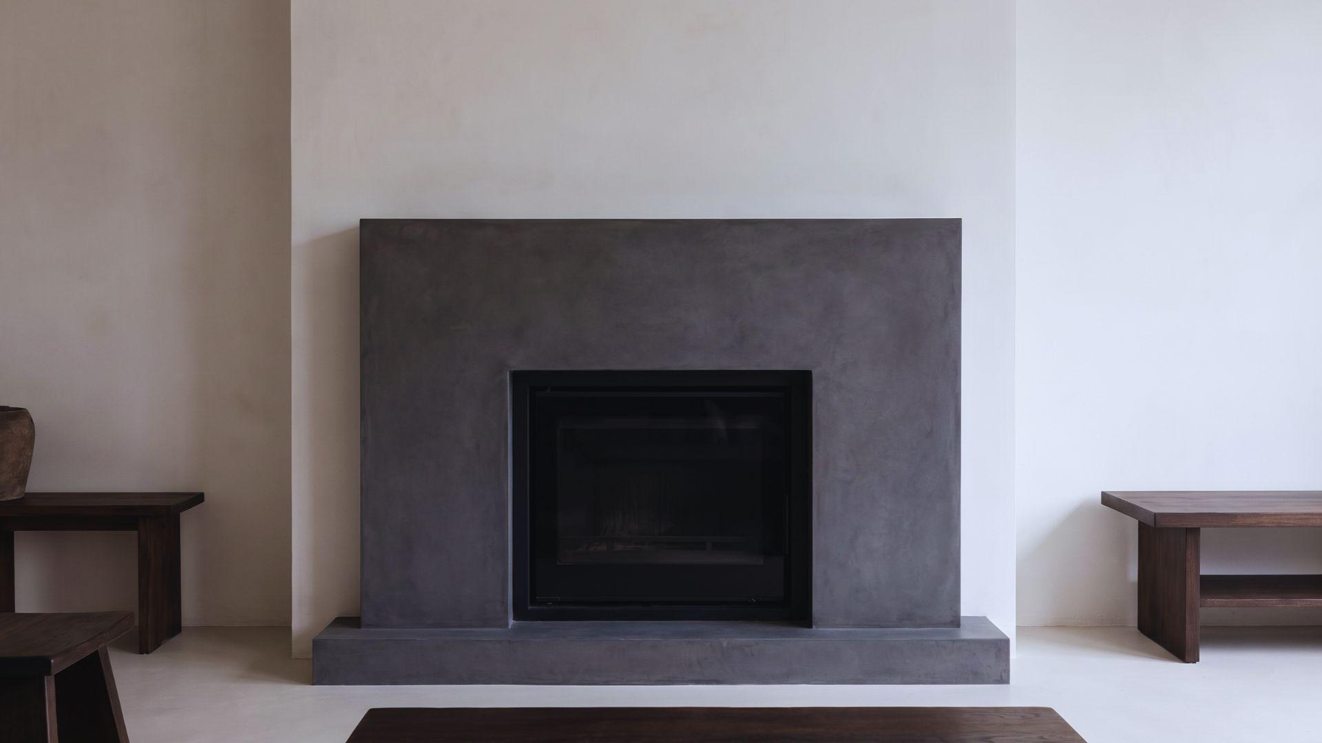Dark grey microcement fireplace surround with a flat matte concrete-like finish.