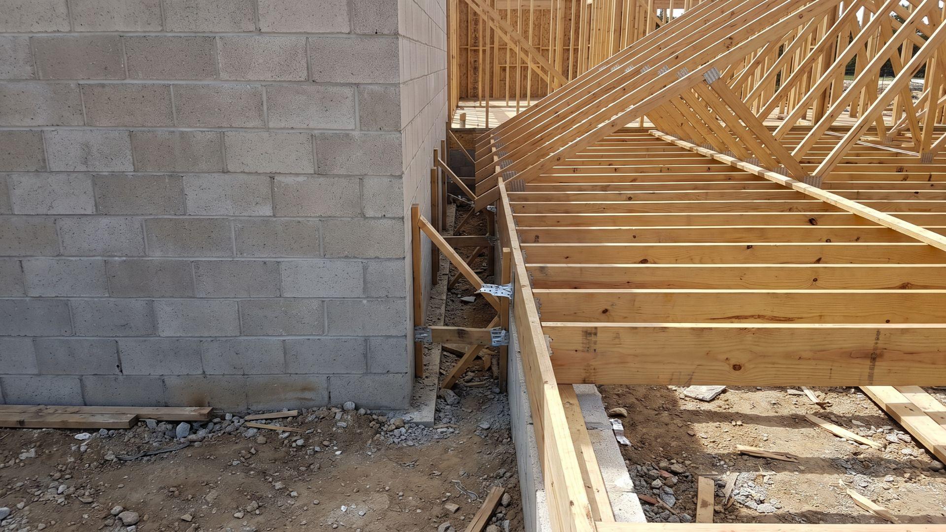 Masonry wall assembly beside combustible wood floor joists and roof framing.