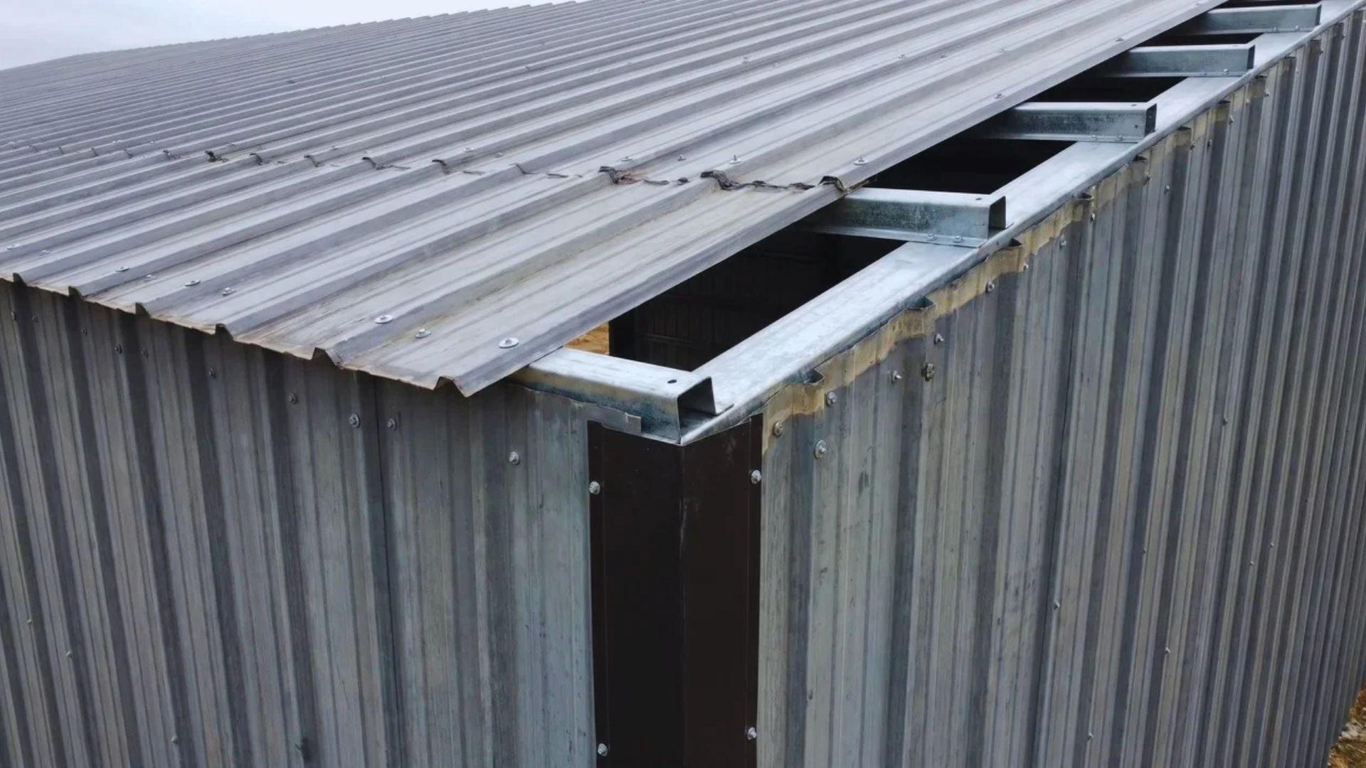 Corrugated metal panels secured to a steel frame with fasteners and trim along the roof edge.