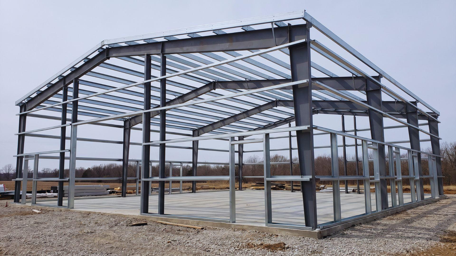 Roof purlins and wall girts connect steel frames around unfinished door and window openings.