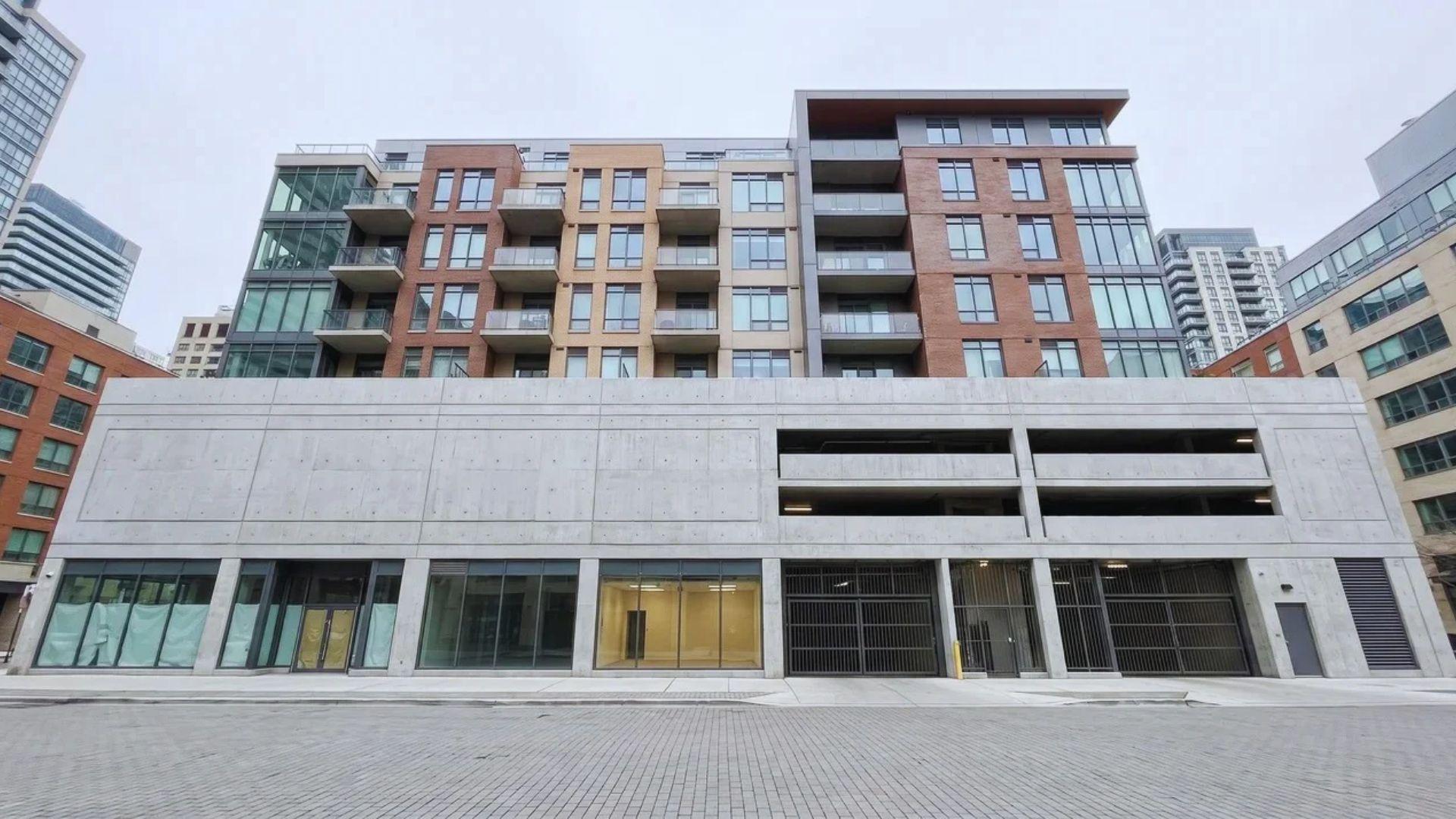 Mixed-use apartment building with a concrete retail and parking base beneath residential floors.