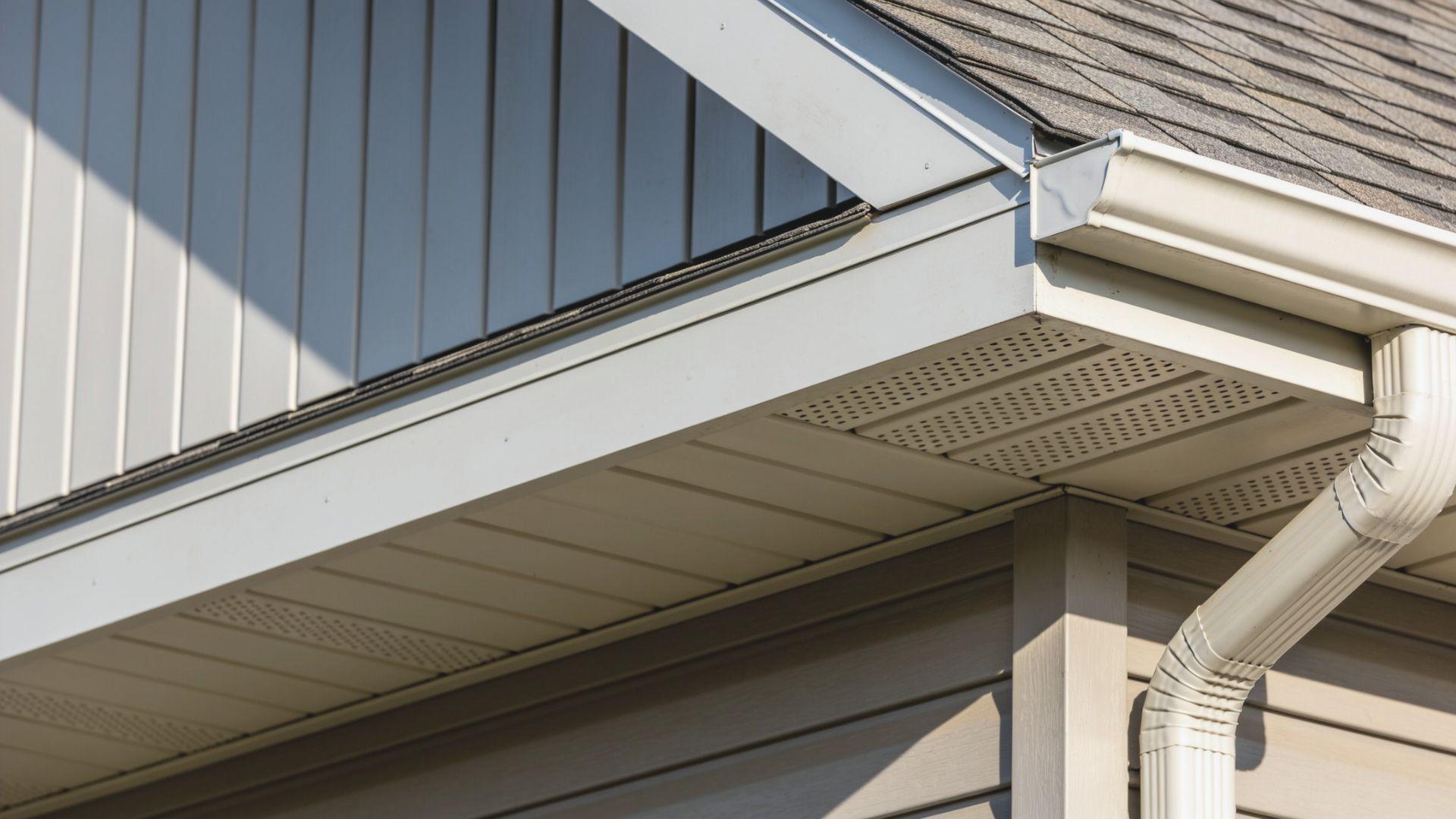 Roof overhang showing vertical fascia boards, vented soffit panels, and an attached rain gutter