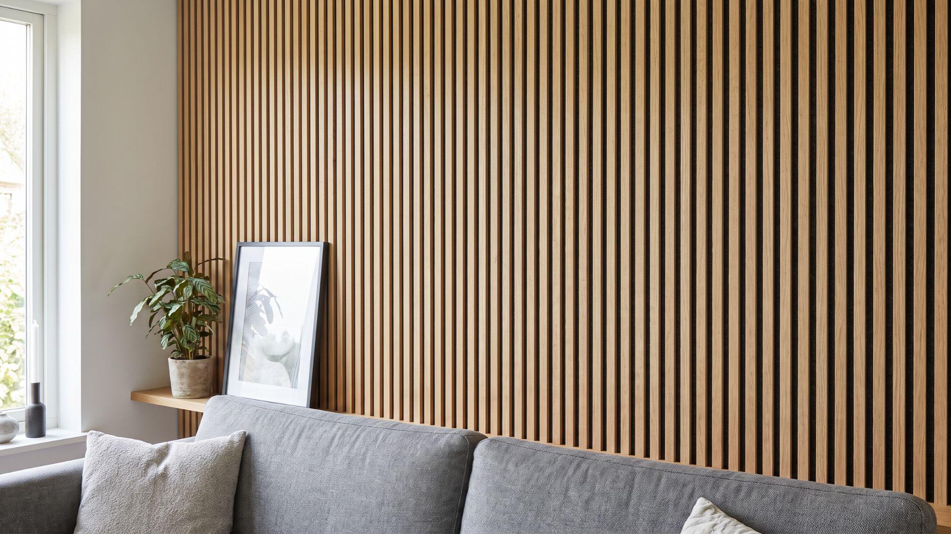 Vertical wood slats mounted over dark felt backing on a living room accent wall.
