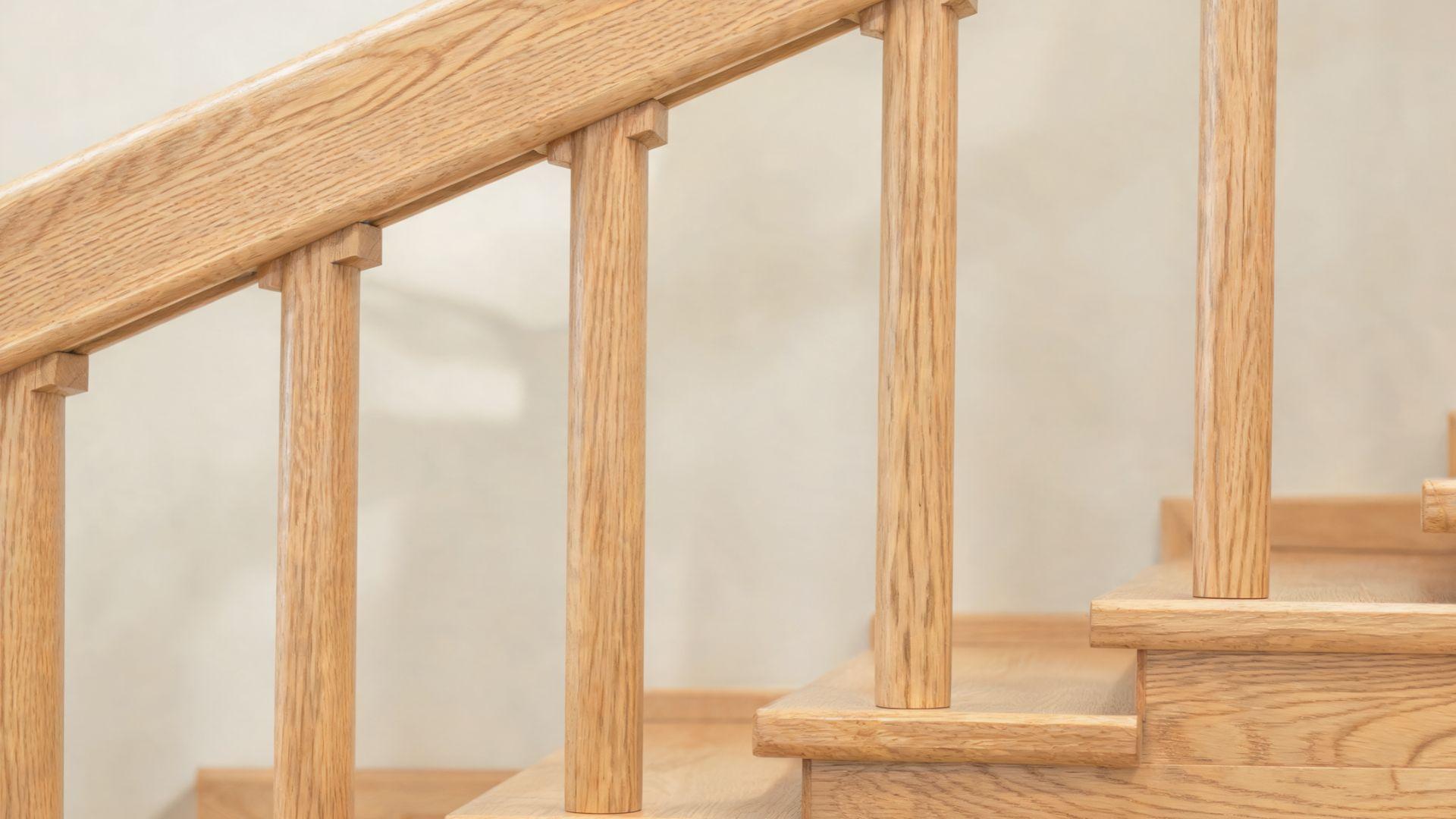 Vertical wooden balusters fitted between a staircase handrail and the steps