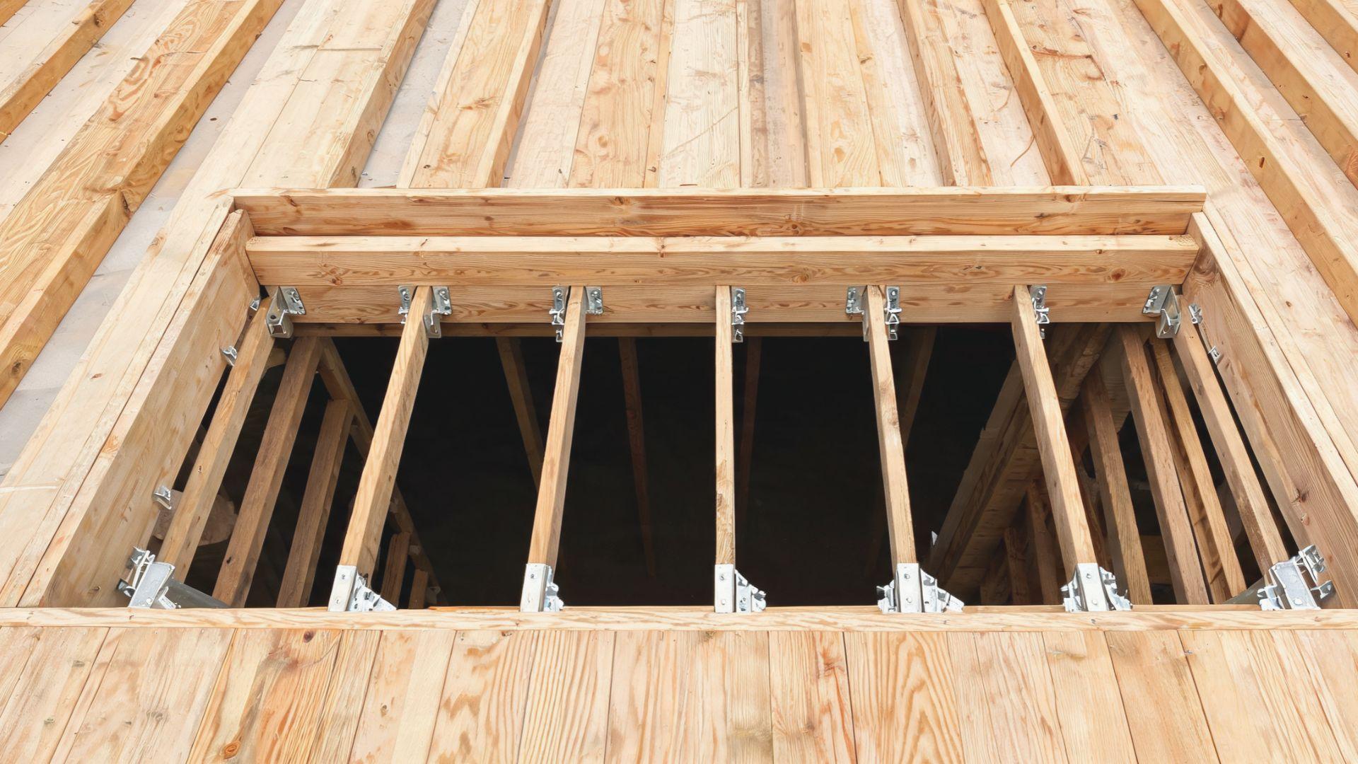 Wooden stairwell header spanning a floor opening beside adjoining floor joists