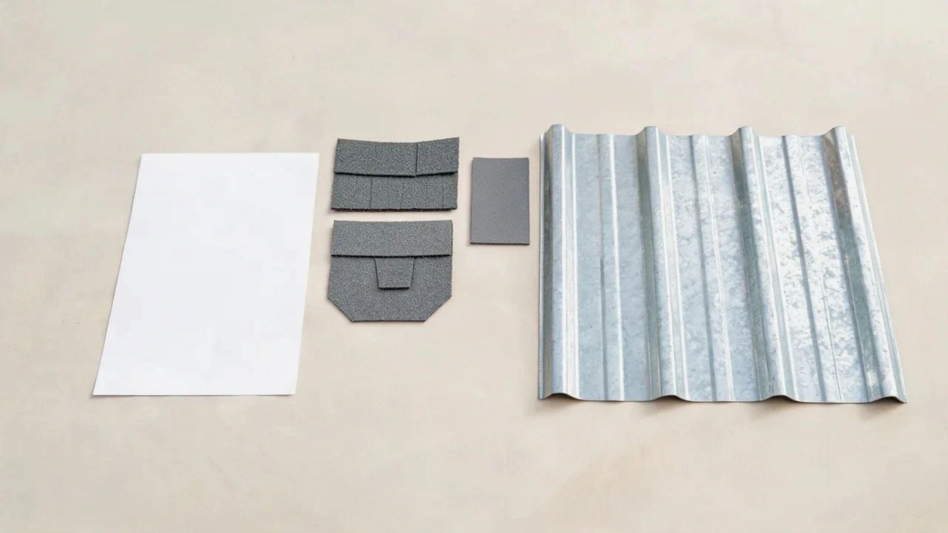 Metal roof panel sample beside an estimate sheet and roofing material samples.