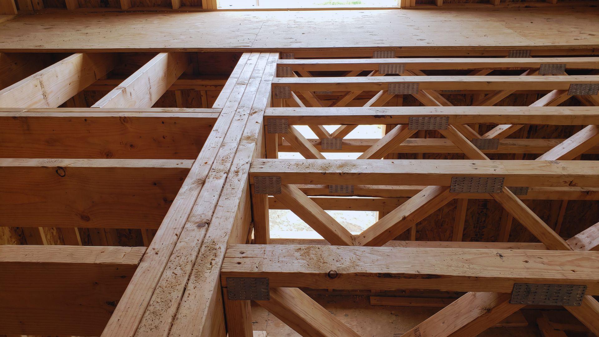 A wooden joist and a triangulated truss support a floor deck with their structural members exposed.