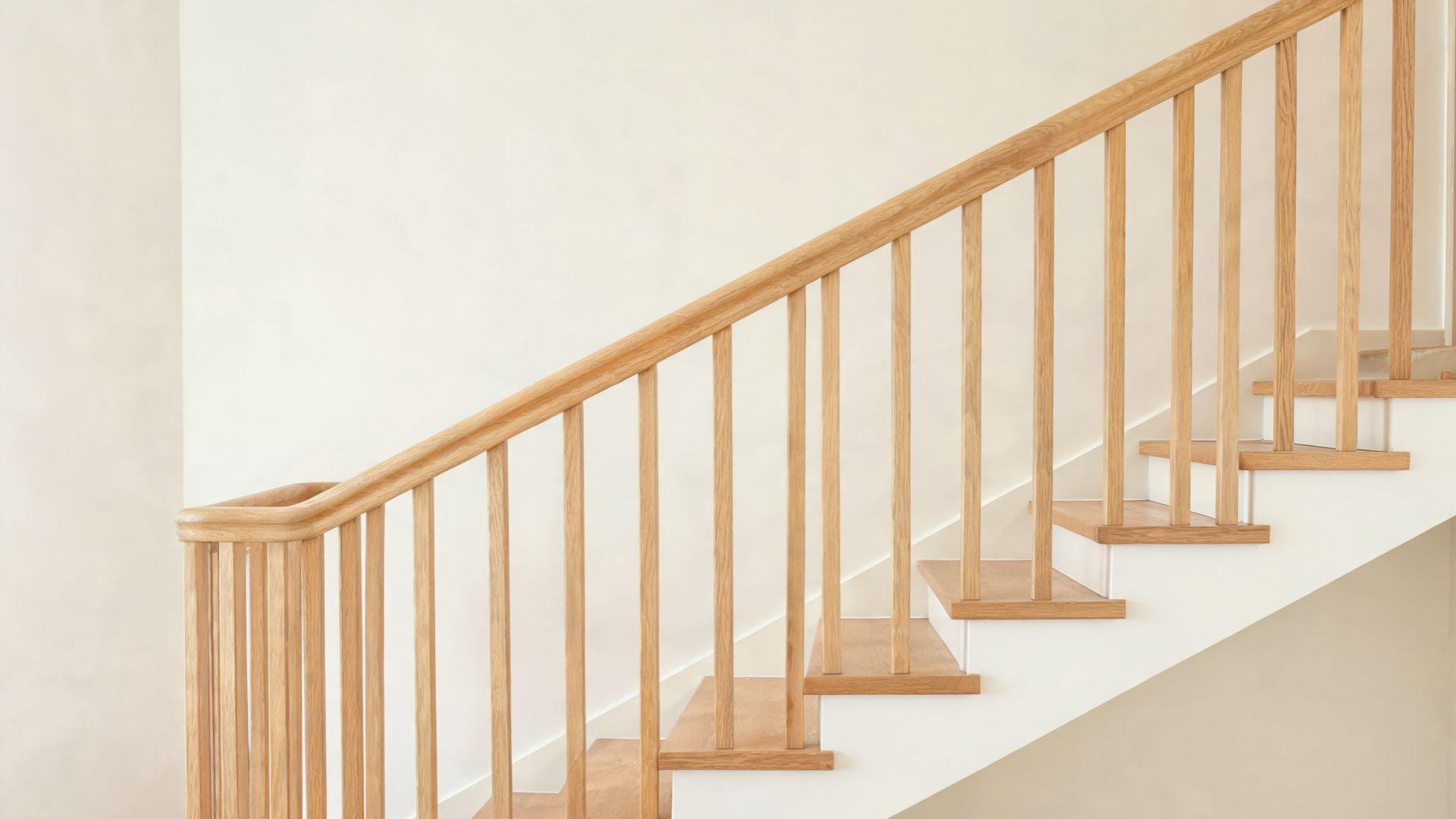 Wooden staircase balustrade with handrail, vertical balusters, and base rail