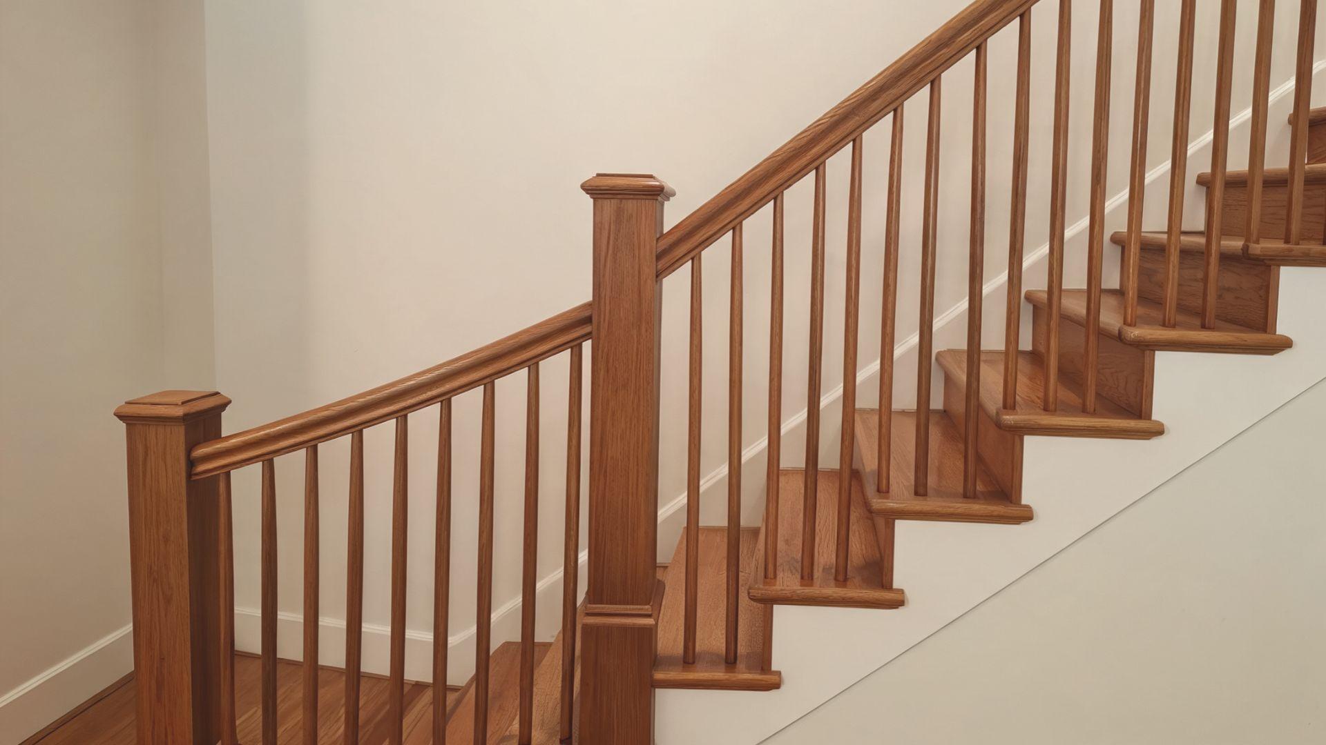 Wooden staircase handrail running above balusters between supporting newel posts